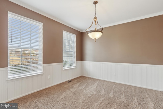 unfurnished room featuring carpet floors, a wainscoted wall, crown molding, and visible vents