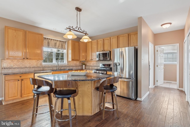 kitchen with stainless steel appliances, dark wood-type flooring, a kitchen breakfast bar, a center island, and pendant lighting