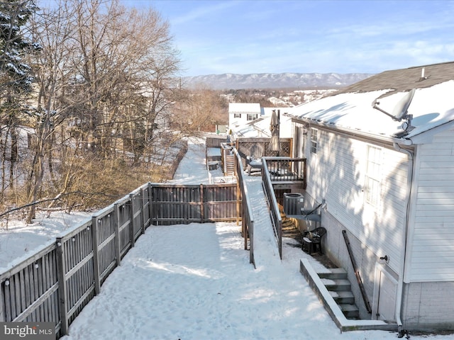 yard layered in snow with a deck with mountain view and cooling unit