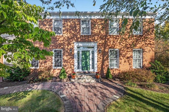 colonial home featuring brick siding and a front lawn