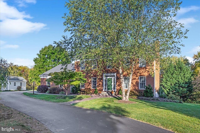 obstructed view of property with a front lawn and brick siding