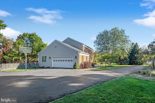 view of front of property featuring driveway, a garage, and fence