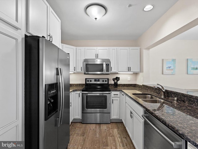 kitchen featuring dark stone countertops, stainless steel appliances, sink, and white cabinets