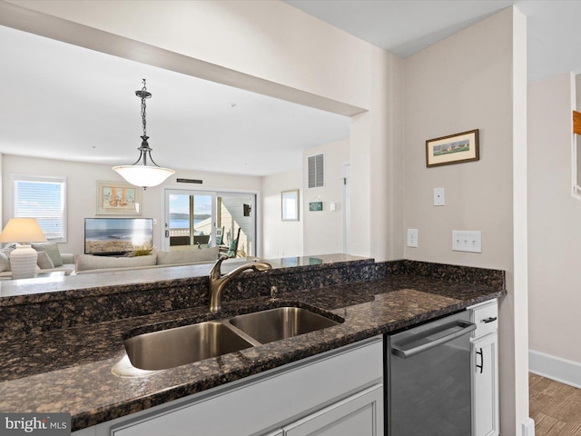 kitchen with pendant lighting, dishwasher, sink, dark stone counters, and plenty of natural light