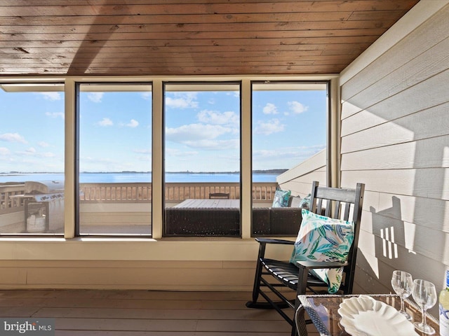 sunroom featuring a water view, a healthy amount of sunlight, and wood ceiling