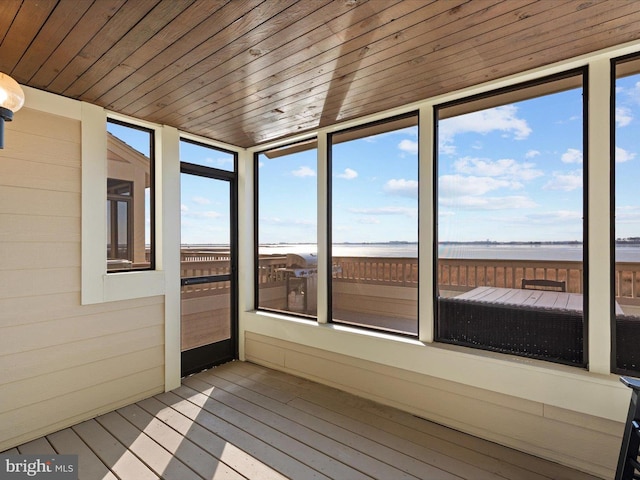 unfurnished sunroom featuring a water view and wood ceiling