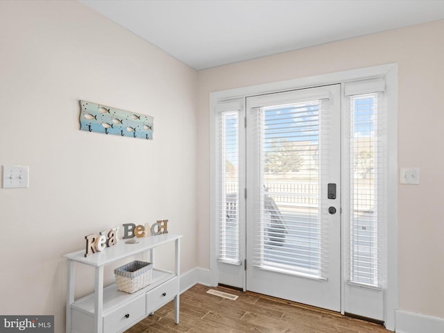 doorway with hardwood / wood-style flooring and a healthy amount of sunlight