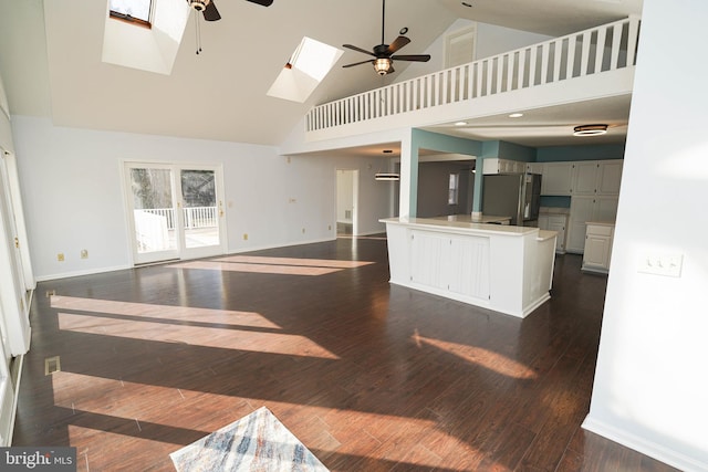 kitchen featuring stainless steel fridge, ceiling fan, a skylight, a kitchen island, and dark hardwood / wood-style flooring