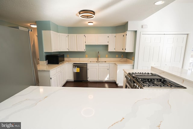 kitchen featuring light stone counters, sink, white cabinets, and appliances with stainless steel finishes