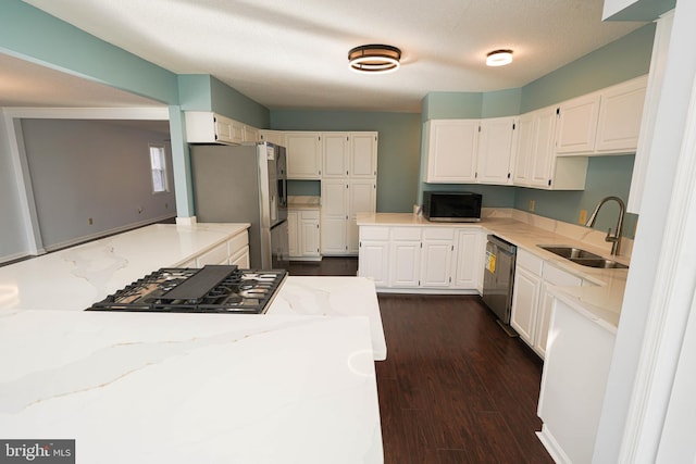 kitchen with light stone counters, sink, stainless steel appliances, and white cabinets