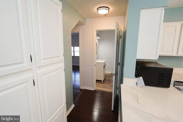 hall with dark hardwood / wood-style flooring, sink, and a textured ceiling