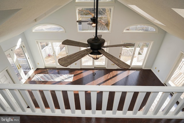 stairs with a textured ceiling, wood-type flooring, high vaulted ceiling, and ceiling fan