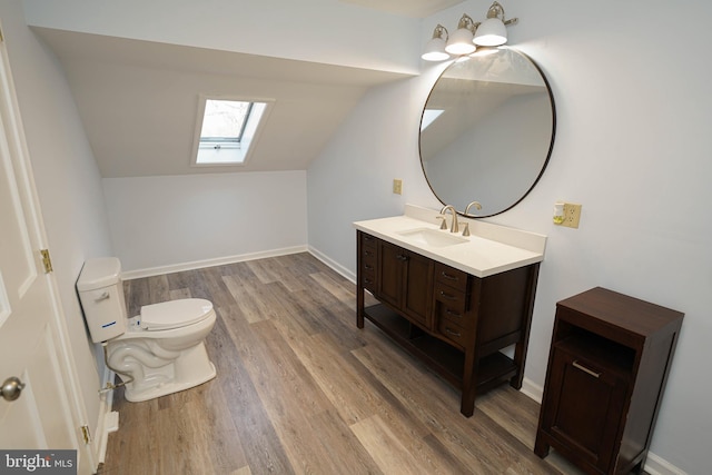 bathroom with hardwood / wood-style flooring, vanity, vaulted ceiling with skylight, and toilet