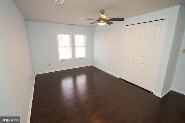 unfurnished bedroom with dark wood-type flooring, a closet, ceiling fan, and a textured ceiling