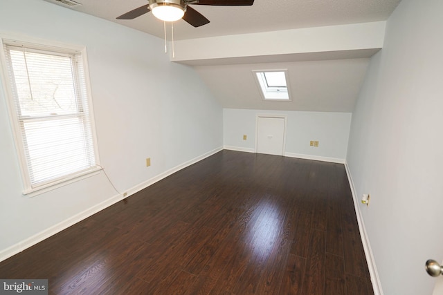 additional living space with ceiling fan, dark hardwood / wood-style floors, and vaulted ceiling with skylight