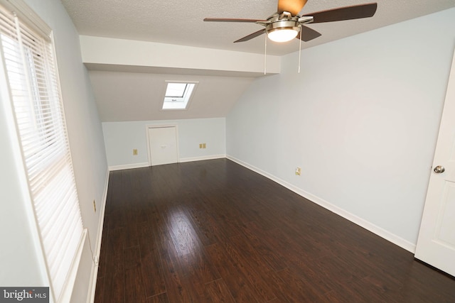 bonus room with dark wood-type flooring, ceiling fan, lofted ceiling with skylight, and a textured ceiling