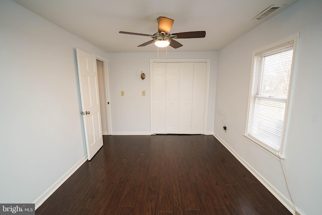 unfurnished bedroom featuring dark wood-type flooring, a closet, and ceiling fan