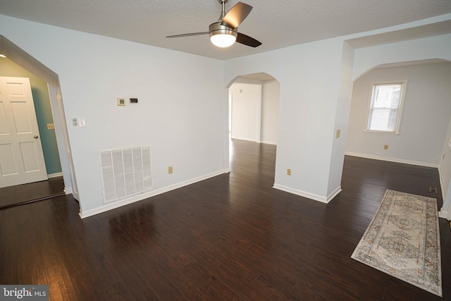 unfurnished room featuring dark wood-type flooring, ceiling fan, and a textured ceiling