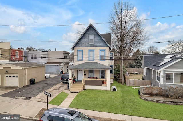 view of front of home featuring a garage, covered porch, and a front yard