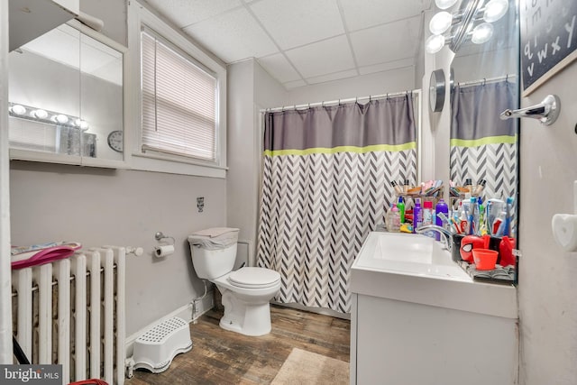 bathroom with radiator, a paneled ceiling, vanity, wood-type flooring, and toilet