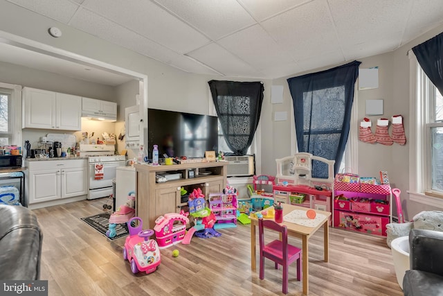 playroom featuring plenty of natural light, a paneled ceiling, light wood-type flooring, and cooling unit