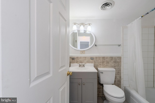 full bathroom with vanity, tile walls, shower / bath combo with shower curtain, and toilet