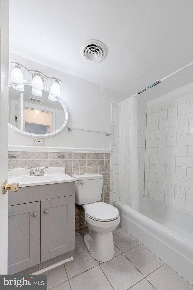 full bathroom featuring toilet, shower / bathtub combination with curtain, tile patterned flooring, and tile walls