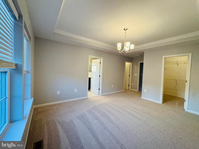 unfurnished bedroom with a walk in closet, carpet flooring, a chandelier, and a closet