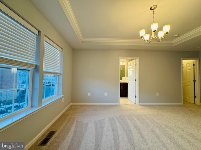 empty room with crown molding, light carpet, an inviting chandelier, and a tray ceiling