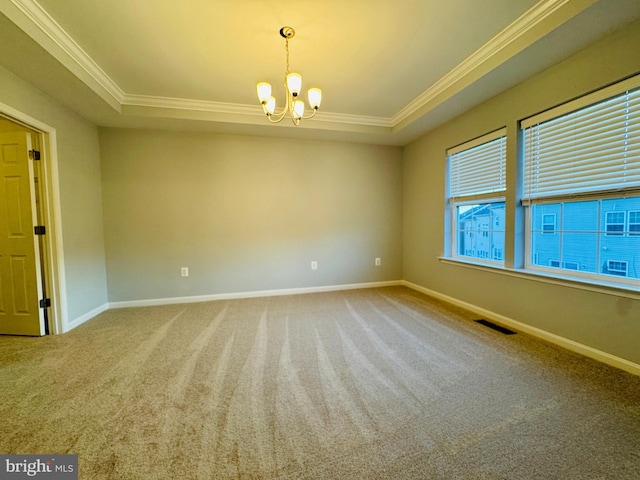 spare room with a raised ceiling, ornamental molding, carpet floors, and an inviting chandelier