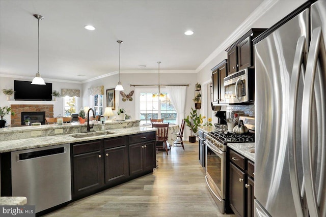 kitchen featuring dark brown cabinets, sink, stainless steel appliances, and pendant lighting