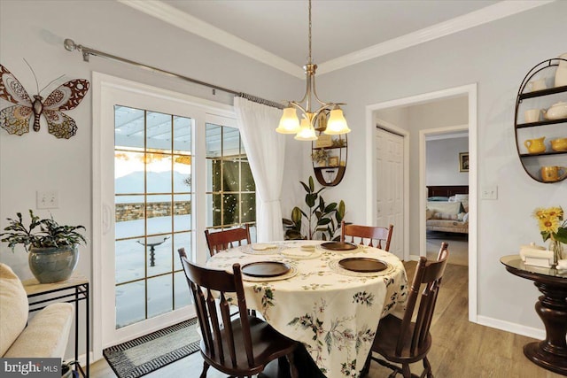 dining space featuring crown molding, light hardwood / wood-style floors, a water view, and a notable chandelier