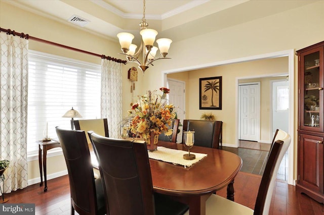 dining room with a tray ceiling, dark hardwood / wood-style flooring, crown molding, and a chandelier