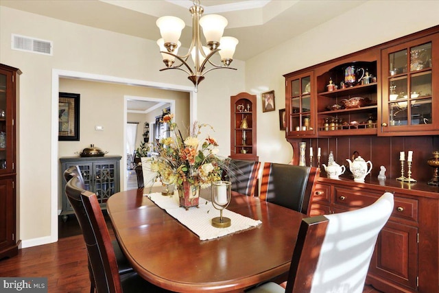 dining area with dark hardwood / wood-style floors, crown molding, and a chandelier