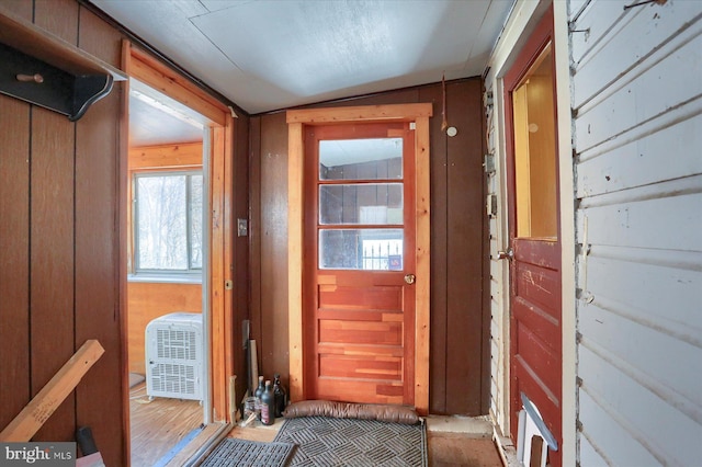 doorway to outside featuring lofted ceiling and wooden walls