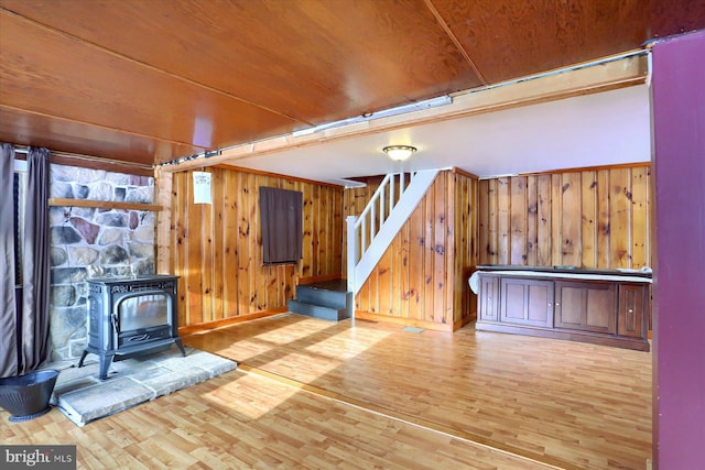 interior space with hardwood / wood-style flooring, wooden ceiling, wood walls, and a wood stove