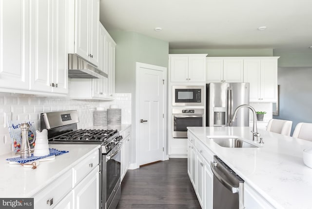 kitchen with white cabinets, appliances with stainless steel finishes, decorative backsplash, sink, and light stone counters