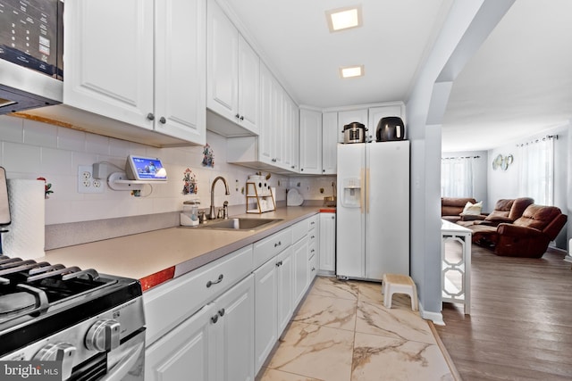 kitchen with decorative backsplash, sink, white cabinetry, and appliances with stainless steel finishes