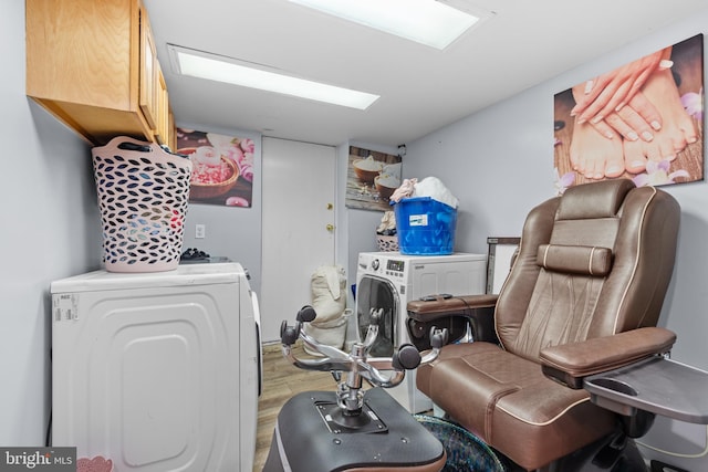 clothes washing area with hardwood / wood-style floors, cabinets, a skylight, and independent washer and dryer