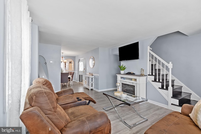 living room with light wood-type flooring, a chandelier, and a fireplace