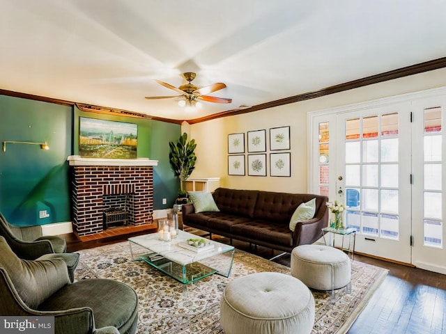 living room featuring hardwood / wood-style flooring, ornamental molding, a brick fireplace, and ceiling fan