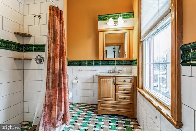 bathroom with walk in shower, plenty of natural light, tile walls, and vanity