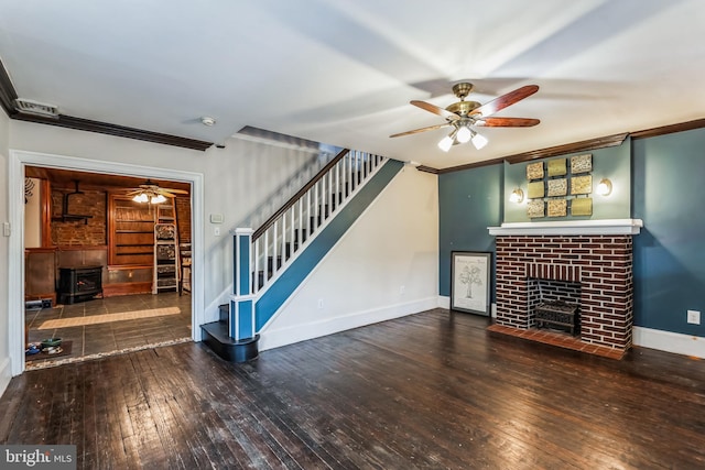 unfurnished living room featuring crown molding, ceiling fan, hardwood / wood-style flooring, and a wood stove