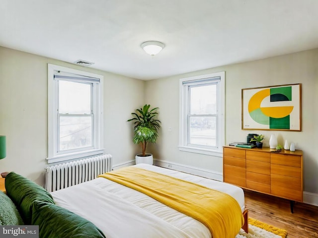 bedroom with radiator heating unit and wood-type flooring