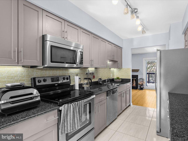 kitchen featuring sink, light tile patterned floors, stainless steel appliances, and dark stone countertops