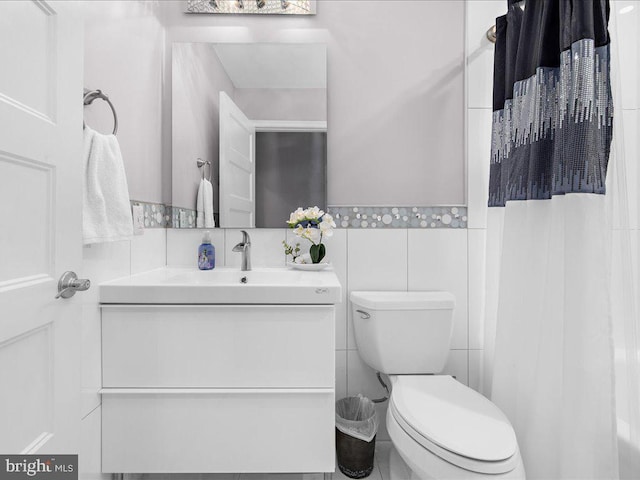 bathroom with toilet, tile walls, vanity, and curtained shower