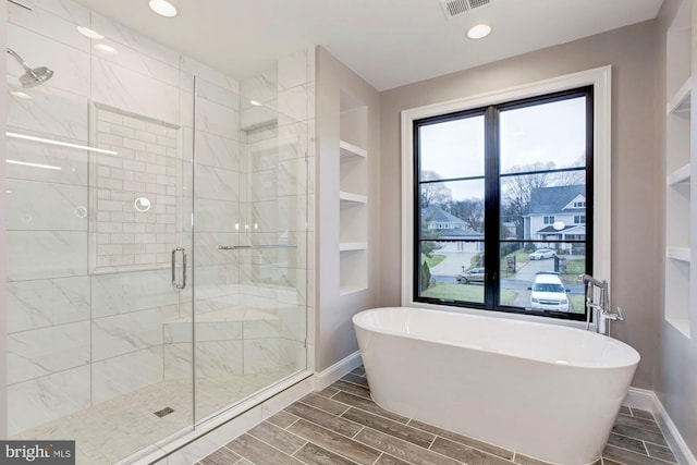 full bathroom with a stall shower, baseboards, wood finish floors, a freestanding tub, and recessed lighting