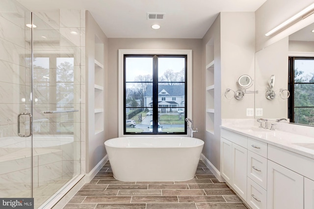 full bathroom with a sink, visible vents, a soaking tub, wood tiled floor, and a stall shower