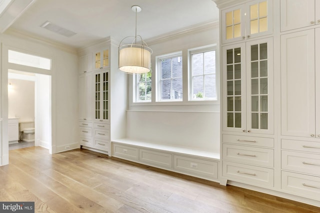 unfurnished dining area featuring light wood-style flooring, visible vents, and crown molding