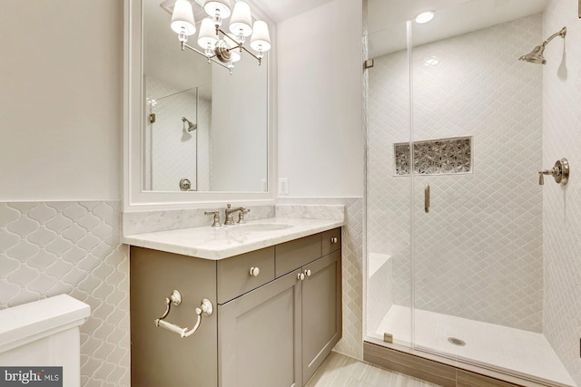 full bath with a stall shower, wainscoting, and vanity